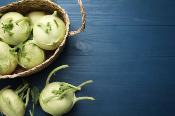 plantas enteras de kohlrabi sobre mesa de madera azul, tendido plano. espacio para texto - kohlrabi turnip kohlrabies cabbage fotografías e imágenes de stock