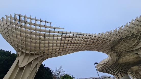 Sevilla, Spain – March 13, 2022: Detail of the Metropol Parasol, known as the Mushrooms (Spanish: Las Setas), is a structure with two columns that hold the access elevators to a famous viewpoint.