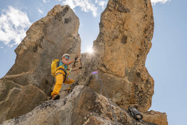 istock Low angle view of female climbing reaching mountain peak 1395933812