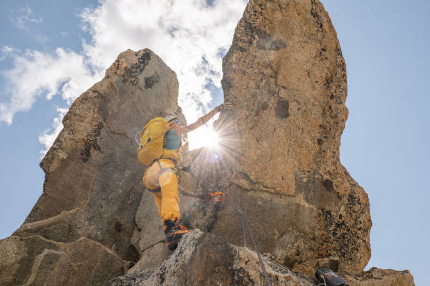 istock Low angle view of female climbing reaching mountain peak 1395933990