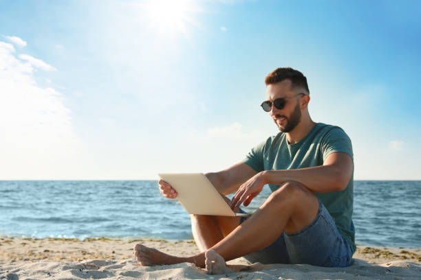istock Man working with laptop on beach. Space for text 1395934545