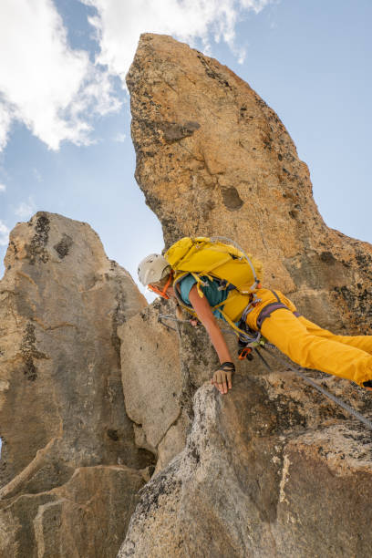 istock Low angle view of female climbing reaching mountain peak 1395934699