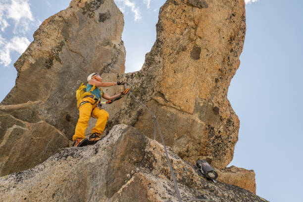 istock Low angle view of female climbing reaching mountain peak 1395934740