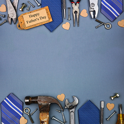 Happy Fathers Day gift tag with double border of ties and tools on a square blue grey paper background. Top down view with copy space.