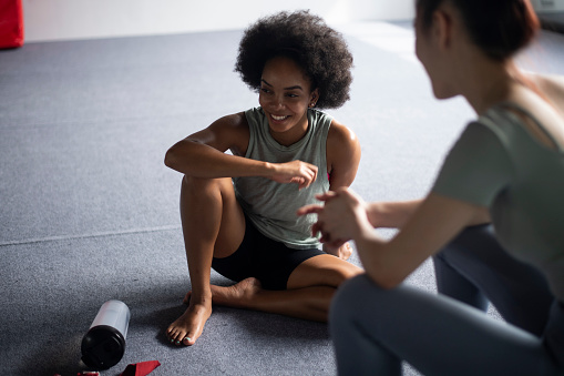 African American Woman chatting with her chinese friend after a workout session