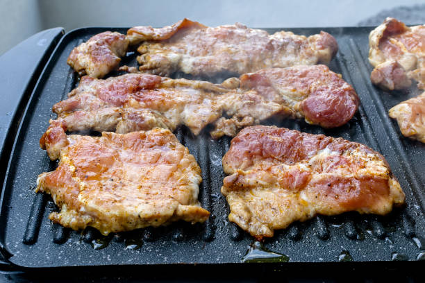 Juicy pork neck steaks on teflon barbecue grill