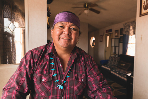 A mature indigenous Navajo man poses for a portrait in the kitchen of his mobile home. Image taken on the Navajo Reservation, Arizona.