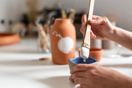 Ceramist painting a clay vase in an atelier