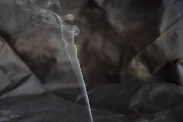Closeup of smoke from burning incense stick on black background