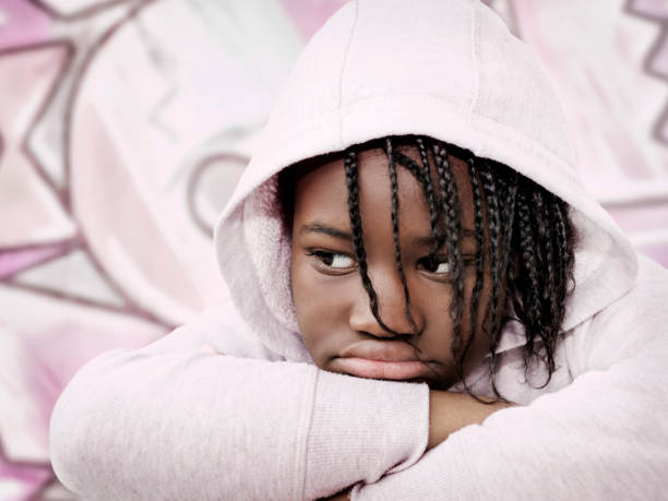 retrato de una chica enojada con rastas que llevaba una sudadera con capucha rosa claro, de doce años, foto - anger child braids braided fotografías e imágenes de stock