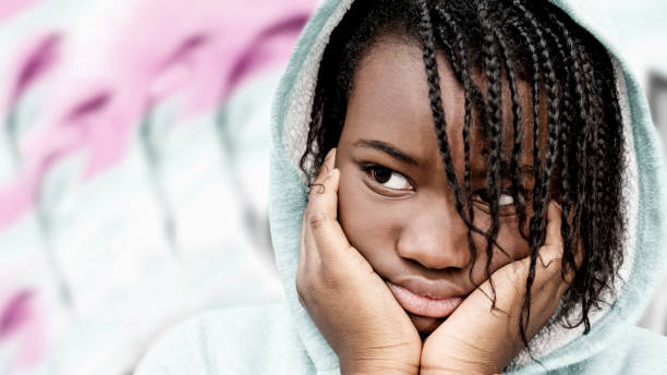 retrato de una chica enojada con rastas que llevaba una sudadera con capucha rosa claro, de doce años, foto - anger child braids braided fotografías e imágenes de stock