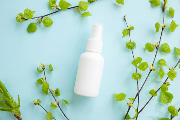 istock White cosmetic spray bottle and birch branches with young small leaves on blue background. Mockup branding. Skincare beauty and liquid antibacterial spray. Natural Body mist. Front view, flat lay. 1395945996