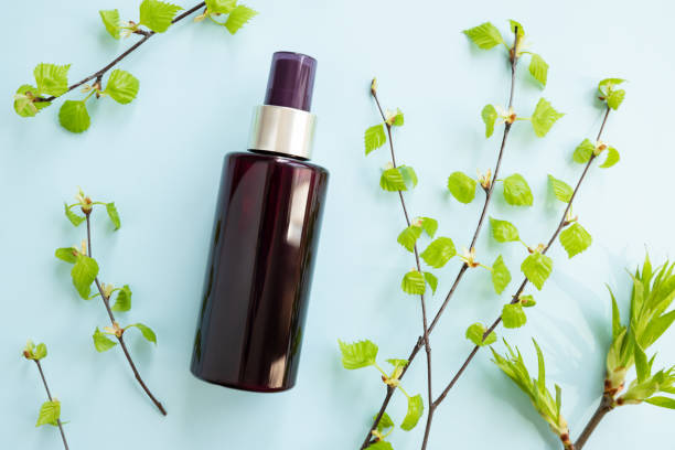 istock Brown cosmetic spray bottle and birch branches with young small leaves on blue background. Mockup. Skincare beauty and liquid antibacterial spray. Natural Body mist. Front view, flat lay. 1395946726