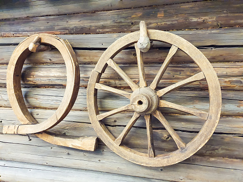 Old wooden wheel and wooden clamp or yoke on wall of vintage log house. Closeup