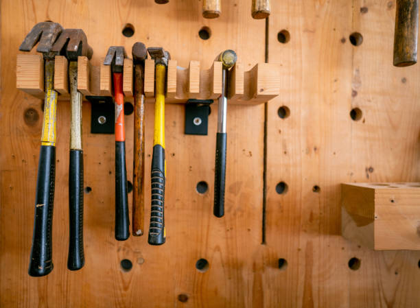 Various Size and Shape Used Hummers Hand Tools hanging on the wall in the carpentry workshop.