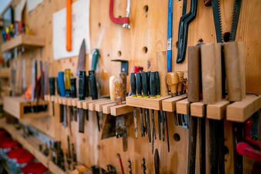 Shelf with hand tools for woodworking. Various carpenter hand tools hanging on the wall in the carpentry workshop.