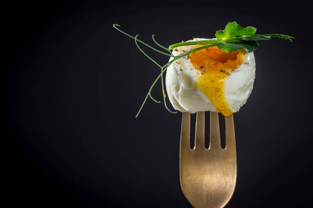 istock Soft-boiled egg with pea microgreens on a fork on a black background, breakfast time, copy space 1395951757
