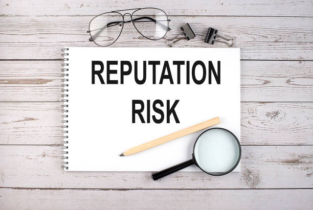 istock Notebook with text REPUTATION RISK on the wooden table with pen, magnifier and glasses 1395951882