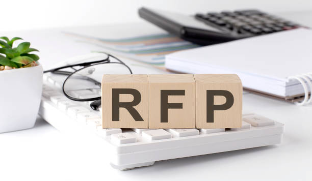 RFP written on a wooden cube on keyboard with office tools stock photo