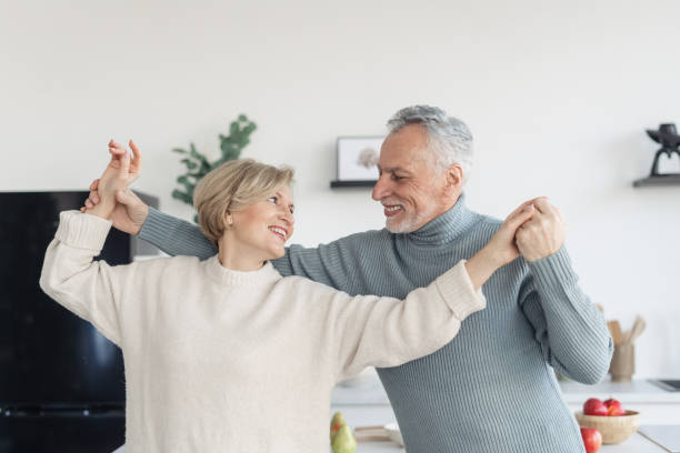 istock Aged couple smiling and dancing in kitchen together 1395952572