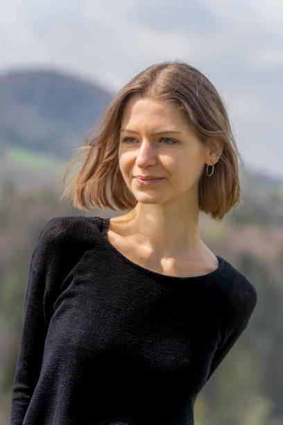 Young beautiful woman with relaxed expression in face in front of Swiss hills. stock photo