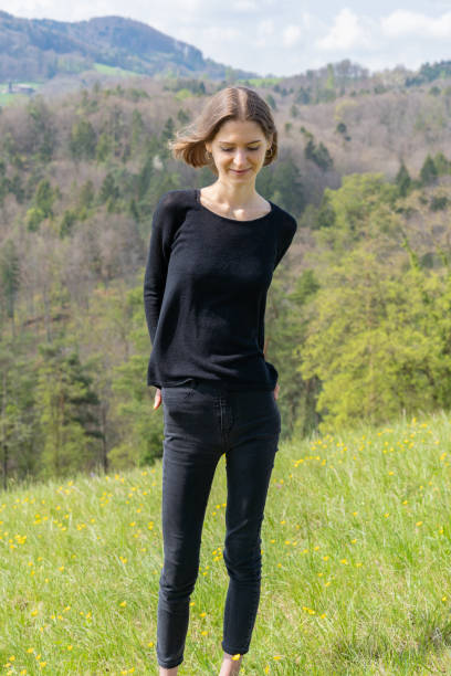 Portrait of young beautiful woman wearing black clothes smiling at camera in nature of Switzerland in springtime. stock photo