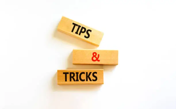 Photo of Tips and tricks symbol. Concept words Tips and tricks on wooden blocks. Beautiful white table, white background. Business, tips and tricks concept. Copy space.