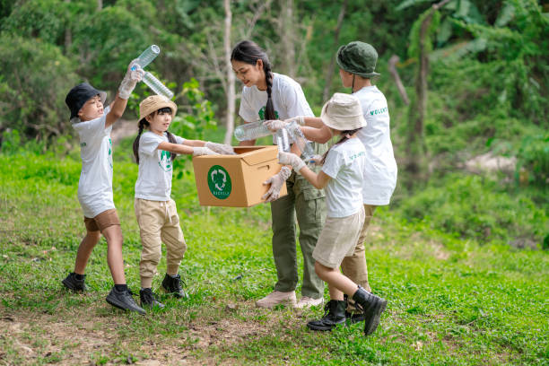 Volunteer Asian and children are collecting plastic bottles into garbage box to reduce global warming and environmental pollution. Volunteering and recycling concept. stock photo