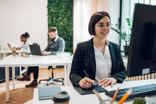 istock Female graphic designer working on a drawing tablet in open space office 1395958422