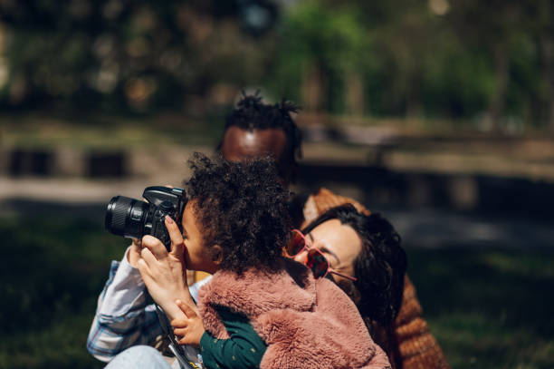 istock Beautiful multiracial family using a digital camera in the park. 1395958483