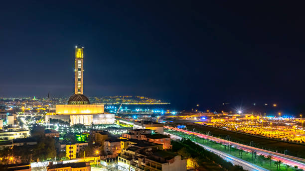 The great mosque of Algiers and the Martyr's Memorial monument Maqam El Chahid by night. Seen from the building of Les Dunes in Lavigerie, Mohammadia. Highway, Ardis parking, green grass and palm trees enlightened. algiers stock pictures, royalty-free photos & images