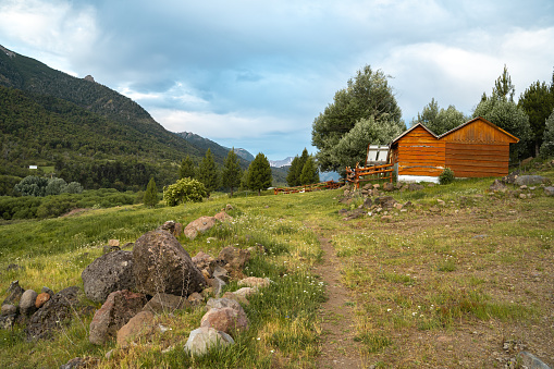 Cabin with trees and pasture in a mountain valley during a cloudy day, Chile