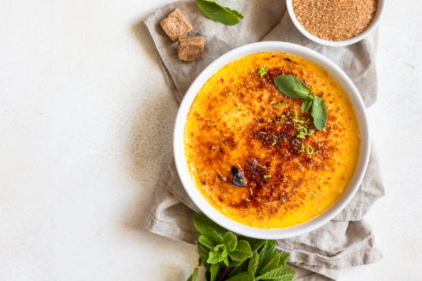 creme brulee com crosta de caramelo e hortelã em pratos de cerâmica branca. famosa sobremesa francesa. deliciosas sobremesas para café ou restaurante. - burnt sugar - fotografias e filmes do acervo