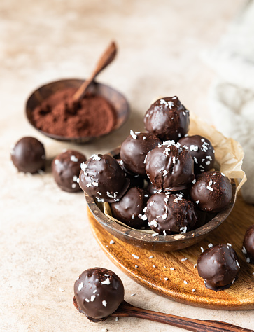 Vegan chickpea and peanut butter candies in chocolate glaze sprinkled with coconut chips. Energy balls. Healthy raw dessert without sugar.