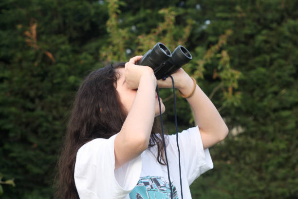 young girl is discovering the surrouding she is looking through a binocular. - children only tree area exploration freshness imagens e fotografias de stock