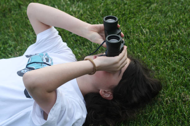 young girl is discovering the surrouding she is looking through a binocular. - children only tree area exploration freshness imagens e fotografias de stock