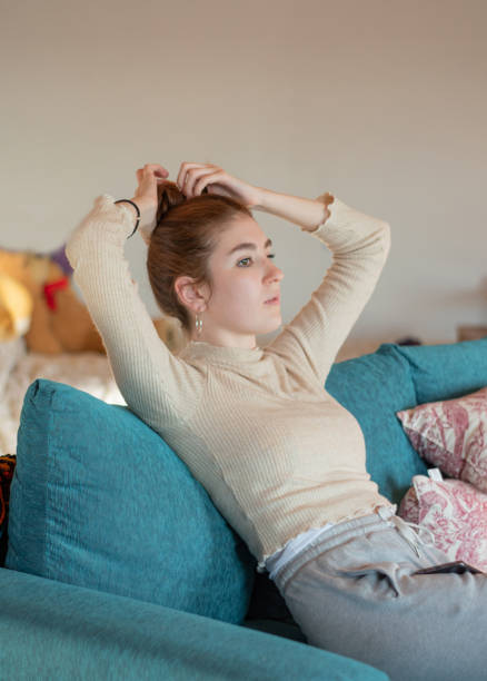 istock girl sitting on sofa doing her hair 1395972180