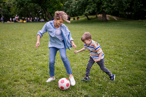 Smiling mother with happy son playing with a ball