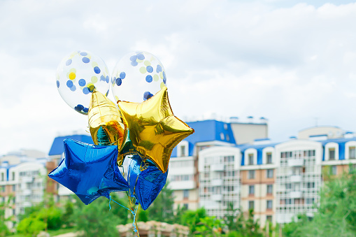 yellow and blue helium balloons on the background of the city. Gift and decoration for a birthday party. Place for text, copy space