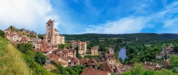 A panoramic view of a charming medieval village perched on a steep cliff and standing high above the river below. Saint-Cirq-Lapopie, Lot Valley, France.