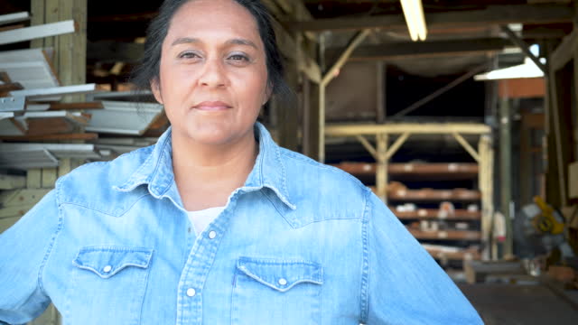 Hispanic woman working at lumberyard, serious