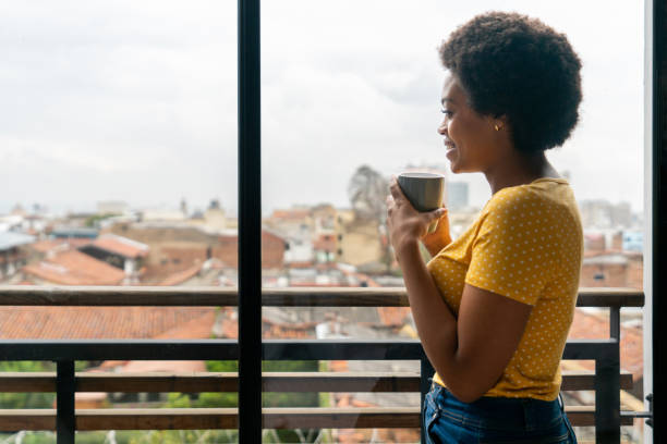 istock Woman drinking a cup of coffee at home while looking at the view 1396019825