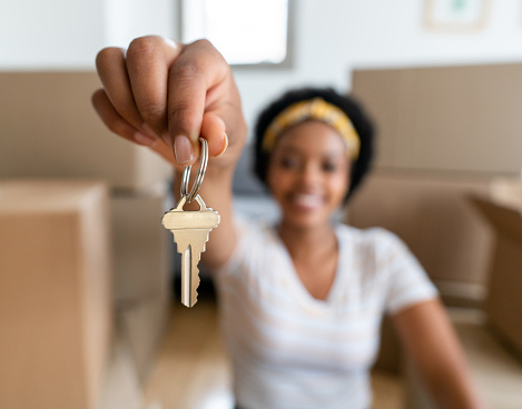 Happy African American woman moving and holding the keys of her new house - focus on foreground