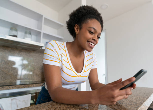 istock Happy woman at home using app on her cell phone 1396020681