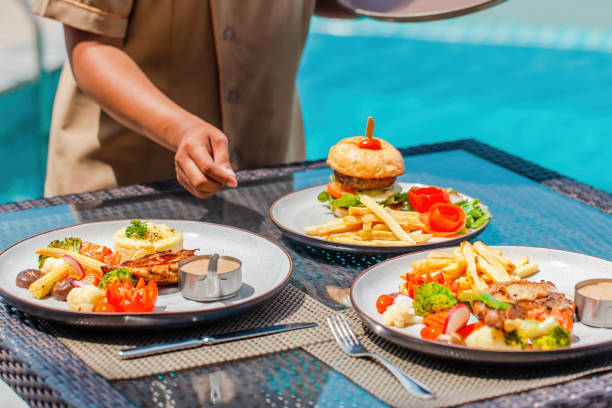 cameriera a mano che serve il pranzo in ristorante in hotel, vacanze, vacanze concetto - dining burger outdoors restaurant foto e immagini stock