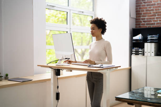donna che usa la scrivania regolabile in piedi in altezza in ufficio - posizione corretta foto e immagini stock
