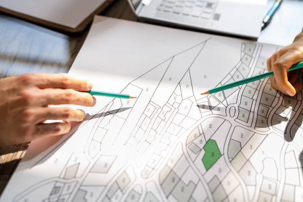 istock Human Hand Holding Pencil Over Cadastre Map 1396023705