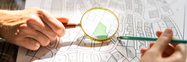 istock Human Hand Holding Magnifying Glass Over Cadastre Map 1396023709