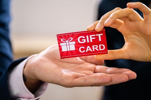Close-up Of Two Businesspeople Hand Holding Red Gift Card