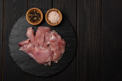 fresh raw rabbit meat on a black mantelpiece with pink salt and a mixture of allspice, flat lay, open space